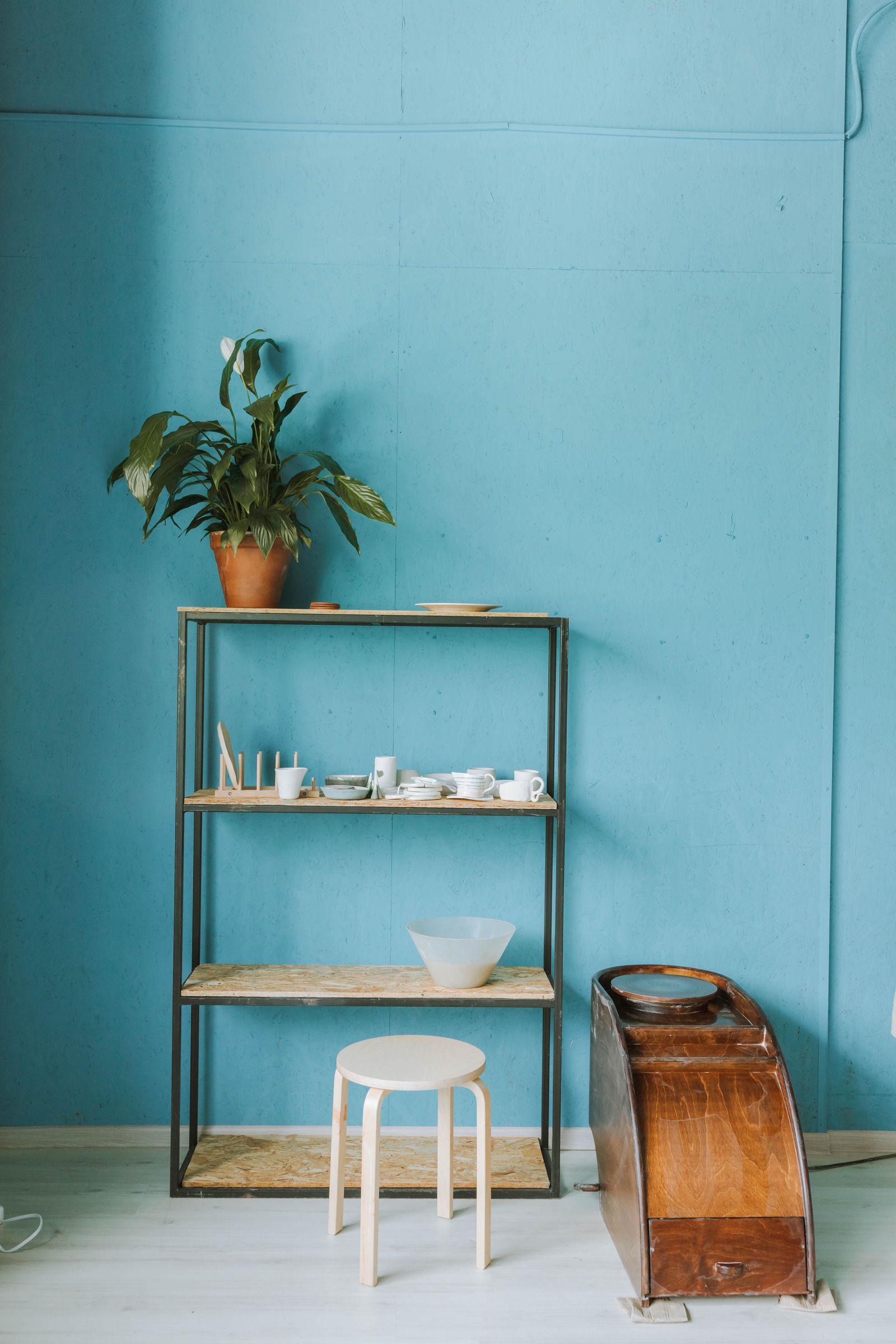 Ceramic pieces on shelves in a pottery workshop with a blue wall
